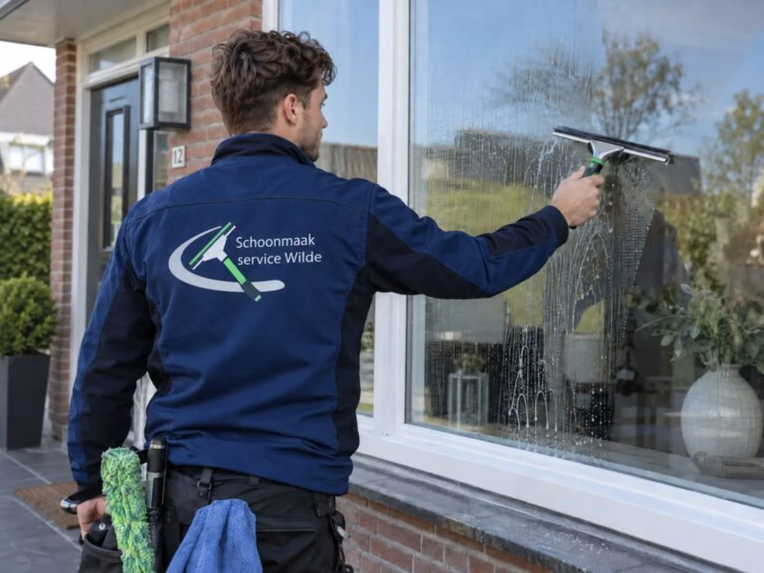 Glazenwasser van Schoonmaakservice Wilde aan het werk bij een woning